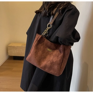 Close-up of brown suede tote bag with quilted pattern and metal chain strap detail