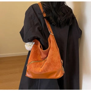 Detail of orange corduroy tote bag with side zipper and plush owl charm accessory
