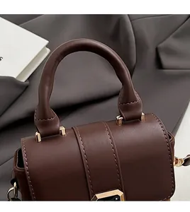 Detailed close-up of dark brown handbag showing curved handle and gold metal lock
