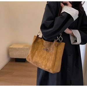Close-up of quilted rhombus pattern on brown suede tote bag with gold metal hardware
