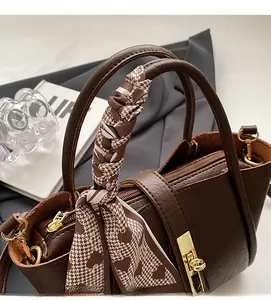 Close-up of dark brown bucket bag featuring a decorative houndstooth silk scarf on handle