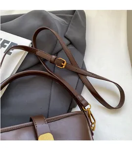 Détail de la bandoulière réglable en cuir marron avec boucle en métal doré chic
