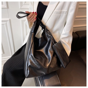 Große schwarze Shopper-Tasche aus glänzendem PU-Leder mit kleiner Tasche am Model