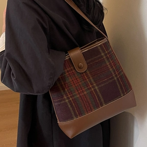 Sac seau à carreaux marron à la mode avec coutures en cuir porté à l'épaule d'un mannequin