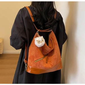 Detailed back view of a brown corduroy tote backpack with a white owl plush accessory