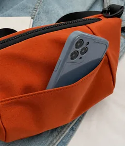 Detail der orangefarbenen Umhängetasche aus Nylon mit offener Fronttasche für Smartphones