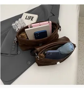 Intérieur spacieux du sac bandoulière matelassé marron contenant tablette, téléphone et parapluie