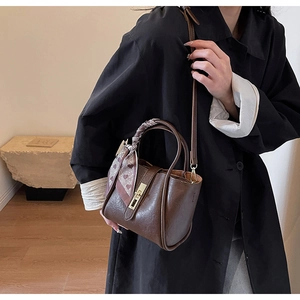 Close-up of vintage brown leather bucket bag with gold clasp and decorative pink scarf