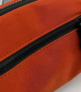 Detail-Makroaufnahme einer orangen Canvas-Tasche mit hochwertigem schwarzen Reißverschluss