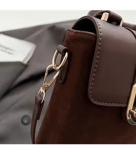 Detail of a brown matte suede crossbody bag with premium gold hardware and sturdy stitching