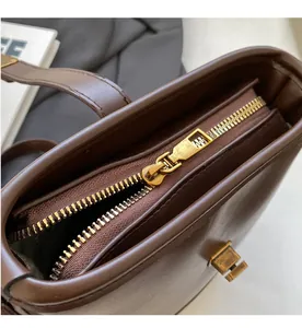 Gros plan sur la fermeture éclair lisse et le fermoir doré vintage du sac seau marron