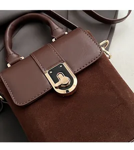 Close-up of golden metal lock and mixed suede texture on a vintage brown handbag