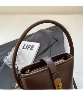 Vue détaillée de la poignée en cuir et du fermoir doré sur le sac seau