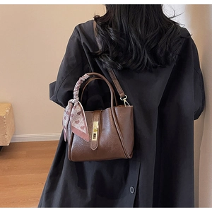 Detail of vintage brown bucket bag with lychee texture and plaid silk scarf handle