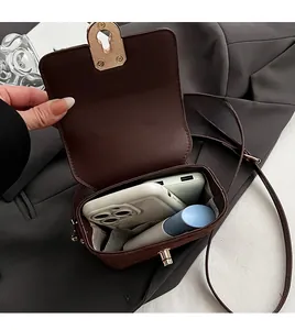 Detail view of the open brown crossbody bag showing spacious interior and golden lock
