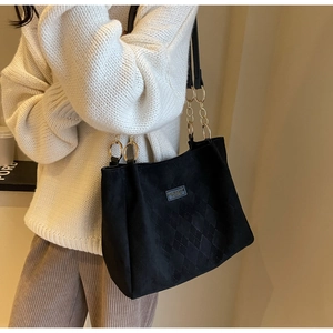 Close-up of black matte suede tote bag with diamond lattice pattern and metal chain strap