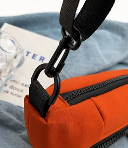 Nahaufnahme des matt schwarzen Metallhakens und Reißverschlusses der orangen Segeltuchtasche