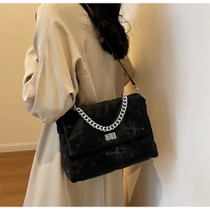 Détail du sac bandoulière en velours noir avec chaîne argentée et fermoir sur un mannequin