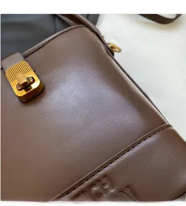 Gros plan sur cuir grainé marron foncé avec bouton-pression métallique doré