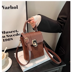 Detail of vintage brown crossbody bag with metal buckle and suede patchwork design