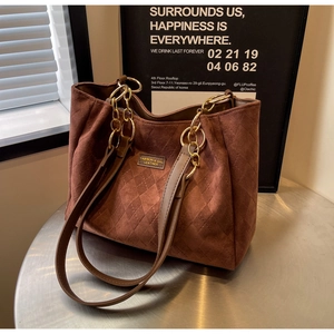 Close-up of brown suede tote bag with quilted diamond pattern and chain strap