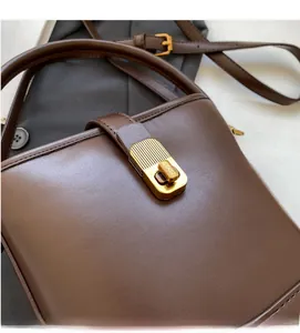 Détail du sac seau en cuir marron foncé avec boucle métallique dorée à rayures verticales
