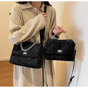 Gros plan du sac à main matelassé noir avec chaîne et fermoir en argent deux tailles