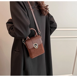 Rear view of brown vintage square bag with gold twist lock on black coat
