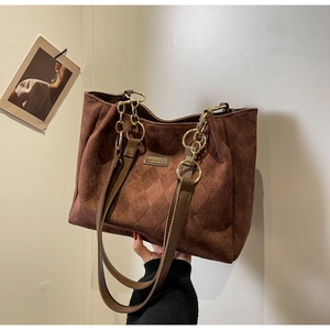 Detailed view of brown quilted tote bag with gold chain and matte textured finish