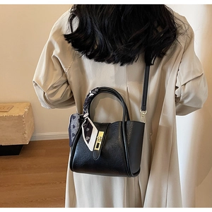 Detail of black bucket bag with heart scarf and metal lock on a model back view