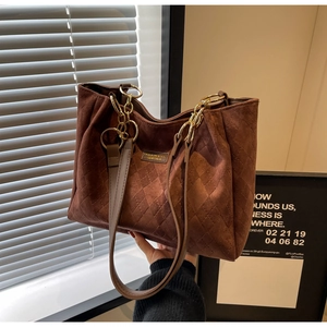 Detail of caramel brown quilted tote bag with matte texture and chain strap accents