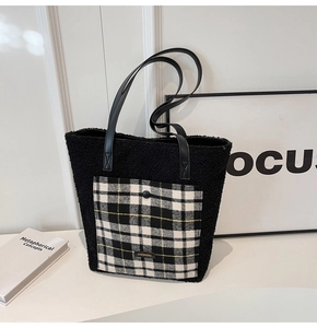 Close-up of black fleece tote bag with a contrast plaid pocket and refined faux leather straps