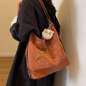 Caramel tote bag with corduroy paneling and owl charm shown on a female model