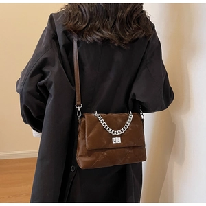 Détail du sac bandoulière matelassé marron foncé avec chaîne argentée et fermoir rotatif