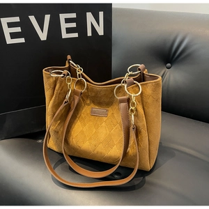Detail of brown quilted tote bag with suede texture and gold chain strap hardware