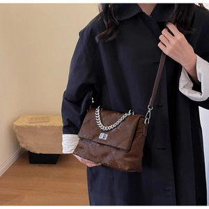 Détail du sac bandoulière marron matelassé avec chaîne argentée et fermoir pivotant