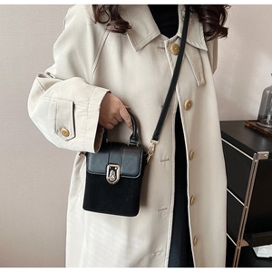 Detail of black crossbody bag featuring matte suede and smooth leather with gold clasp