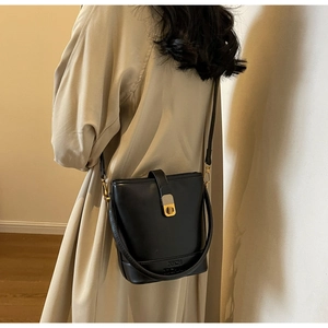 Détail du sac seau en cuir noir avec fermoir doré et logo de marque en bas