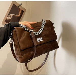 Détail d'un sac bandoulière en daim matelassé marron avec chaîne argentée et fermoir