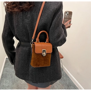 Detail of vintage brown suede crossbody bag with gold metal buckle and leather shoulder strap