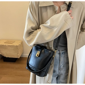 Vue détaillée du sac seau en cuir noir avec fermoir doré et bandoulière sur mannequin