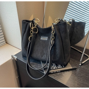 Close-up of black frosted tote bag with quilted diamond pattern and metal chain