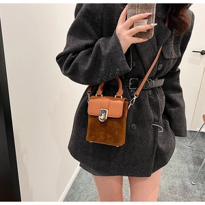 Detail of vintage brown suede crossbody bag with leather flap and gold turn-lock closure