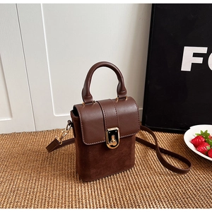 Detail of retro dark brown handbag with matte suede contrast and gold metal lock