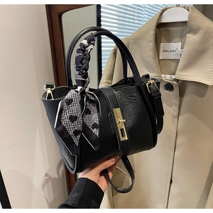 Detail of black bucket bag with gold hardware and heart-shaped houndstooth scarf accessory