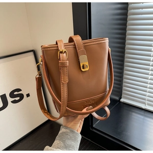 Détail du sac seau en cuir marron avec boucle métallique et logo embossé élégant