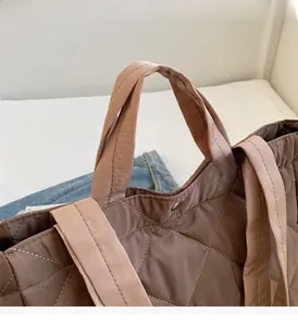 Detail of coffee brown quilted nylon tote bag with silver snap button and wide handle