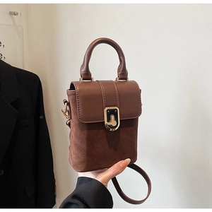 Detail of dark brown mini bag showing smooth leather flap and brushed suede texture