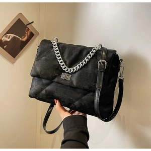 Gros plan du sac bandoulière matelassé noir avec chaîne argentée et fermoir pivotant