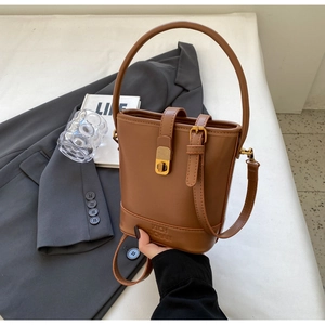Détail du sac seau marron avec fermoir doré et marquage de la marque en bas